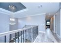 Elegant staircase with wrought iron railing and chandelier, leading to a hallway with views into another room at 2406 High Tides Way, Wesley Chapel, FL 33543
