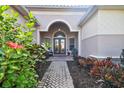Inviting front entrance featuring double doors, brick walkway, arched entry, and decorative landscaping at 5621 Rock Dove Dr, Sarasota, FL 34241