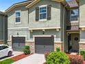 Townhome showcasing attached garages, neutral siding, decorative shutters, and a welcoming front entrance at 11650 Cambium Crown Dr, Riverview, FL 33569