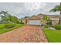 Tan one-story home with brick driveway and landscaping at 736 Mccallister Ave, Sun City Center, FL 33573