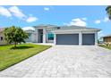 Contemporary home with a three-car garage and elegant paved driveway in a well-manicured yard at 5217 Forbes Ter, Port Charlotte, FL 33981