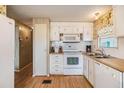 White kitchen with wood flooring and built in microwave at 37743 Mission Hills Ave, Zephyrhills, FL 33541