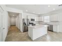 Bright, modern kitchen boasts stainless steel appliances, a center island, and a seamless connection to the hallway at 4275 Big Sky Dr, Spring Hill, FL 34604