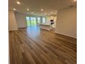 Open-concept floor plan with wood flooring leading to the kitchen and sliding glass doors to the outdoor space at 18204 Beach Ranch Ter, Lakewood Ranch, FL 34211