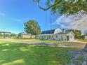 White farmhouse with a large yard, a tree swing, and outbuildings at 4608 Holbrook Rd, Plant City, FL 33565