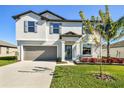 Two-story house with gray garage door and landscaped lawn at 3172 Lytton Hall Dr, Zephyrhills, FL 33540
