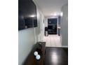 View of a home's hallway, showing dark hardwood floors and a glimpse of the kitchen at 6115 7Th Ave, New Port Richey, FL 34653