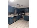 Modern kitchen with teal cabinets, stainless steel appliances, and tile flooring at 6115 7Th Ave, New Port Richey, FL 34653
