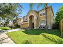 Two-story house with tan exterior, two-car garage and nicely landscaped lawn at 5707 Butterfield St, Riverview, FL 33578