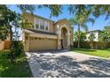 Two-story house with tan exterior, two-car garage, and a well-maintained lawn at 5707 Butterfield St, Riverview, FL 33578