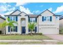 Two-story house with a neutral color palette, blue shutters, and palm trees at 10813 Rolling Moss Rd, Tampa, FL 33647