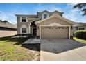 Two-story house with tan siding, large driveway, and landscaped yard at 13951 Caden Glen Dr, Hudson, FL 34669