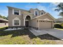 Two-story house with tan siding, large driveway, and landscaped yard at 13951 Caden Glen Dr, Hudson, FL 34669