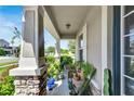 Inviting front porch with stone columns, lush greenery, and a wicker seating area at 13012 Rain Lily Dr, Riverview, FL 33579