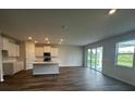 Spacious living room with a modern island kitchen, hardwood floor, and large sliding glass doors to the outside at 708 160Th E Ln, Bradenton, FL 34212