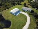 Aerial view of home and detached garage with pond and driveway at 31241 Washington Loop Rd, Punta Gorda, FL 33982