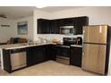 Modern kitchen with dark cabinets, stainless steel appliances, and granite countertops at 11919 Grand Kempston Dr, Gibsonton, FL 33534