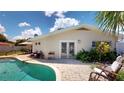 A refreshing pool is surrounded by a brick patio with seating and lush landscaping at 411 Harbor View Ln, Largo, FL 33770