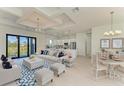 Bright living room with coffered ceilings, seamlessly connecting to a modern kitchen with stainless steel appliances at 15154 Appleton Blvd, Port Charlotte, FL 33981