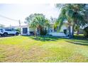 House exterior showcasing a light-colored facade, mature palm trees, and a spacious lawn at 2109 58Th S St, Gulfport, FL 33707