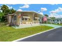 Mobile home with covered porch, landscaping, and American flag at 7048 El Meyers St, Zephyrhills, FL 33541