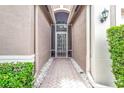 View of front entryway, with a decorative glass door and manicured landscaping at 4949 Sandy Brook Cir, Wimauma, FL 33598