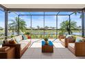 This screened patio features comfortable wicker furniture and a serene waterfront view at 4949 Sandy Brook Cir, Wimauma, FL 33598