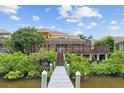 Waterfront home featuring a private wooden dock, screened lanai, and lush tropical landscaping at 1233 Acappella Ln, Apollo Beach, FL 33572