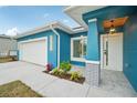 Front exterior of beautiful blue home featuring modern lighting fixtures and gray accents at 272 Diogenes St, Dunedin, FL 34698