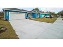 Charming blue single-Gathering home with a wide driveway and a two-car garage, complemented by a neatly manicured lawn at 272 Diogenes St, Dunedin, FL 34698