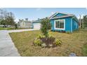 A blue home is adorned with a newly planted tree, surrounded by fresh landscaping, enhancing its curb appeal at 272 Diogenes St, Dunedin, FL 34698