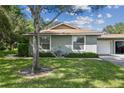 Exterior view of a single story home with a two car garage and mature landscaping at 251 Hidden Brook Dr # 102C, Palm Harbor, FL 34683