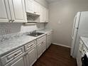 White kitchen cabinets, tile backsplash, and wood-look floors at 4315 Aegean Dr # 126C, Tampa, FL 33611