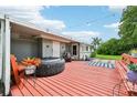 Red wooden deck with hot tub and seating area at 2419 Roxbury Cir, North Port, FL 34287