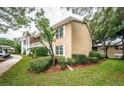 Tan condo building with lush landscaping and walkway at 2156 Masters Ct # 2156, Dunedin, FL 34698