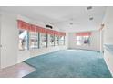 Inviting living room featuring blue carpet, large windows, and neutral walls at 12501 Ulmerton Rd # 131, Largo, FL 33774