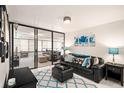 Bright living room with black leather sofa, glass doors, and blue accents at 3211 W Swann Ave # 206, Tampa, FL 33609