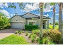 Eye-level view of a two-story house with gray exterior, lush landscaping, and a brick driveway at 19501 Sea Myrtle Way, Tampa, FL 33647