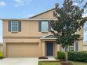 Two-story house with a beige exterior, gray shutters, and a two-car garage at 2110 Purple Orchid Pl, Ruskin, FL 33570