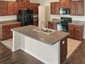 Modern kitchen featuring dark wood cabinets, granite countertops, and a large island at 2110 Purple Orchid Pl, Ruskin, FL 33570