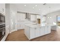 Bright kitchen features white cabinets, stainless appliances, white countertops, large island, and wood floors at 12977 Long Valley Cir, Spring Hill, FL 34609
