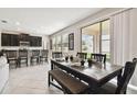 Open dining area with a rustic wooden table, modern chairs, and natural light from sliding glass doors at 11464 Chilly Water Ct, Riverview, FL 33569