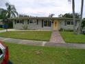 Single-story home featuring a well-manicured lawn and a cozy walkway, all under a pleasant sky at 5805 Oxford Dr, Tampa, FL 33615