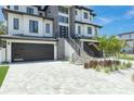 Contemporary home's exterior features a stone facade, modern garage doors, and landscaping at 6012 Kipps Colony E Dr, Gulfport, FL 33707