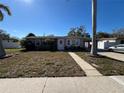 Charming single-story home with mature landscaping and a well-manicured lawn on a sunny day at 15536 Bristol E Cir, Clearwater, FL 33764
