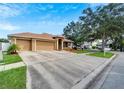 Tan three-car garage home with a red door and nicely landscaped yard at 12739 Standbridge Dr, Riverview, FL 33579