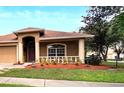 Tan three-car garage home with a red door and nicely landscaped yard at 12739 Standbridge Dr, Riverview, FL 33579