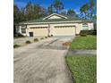 Tan house with green roof, three-car garage, and manicured lawn at 34735 Double Eagle Ct, Zephyrhills, FL 33541