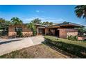 Single-story brick house featuring a porte-cochere and a well maintained yard with tropical plants and hedges at 11921 Lagoon Ln, Treasure Island, FL 33706