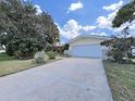 Charming single-story home with a well manicured lawn, mature trees, and a driveway leading to an attached garage at 1385 Embassy Dr, Clearwater, FL 33764